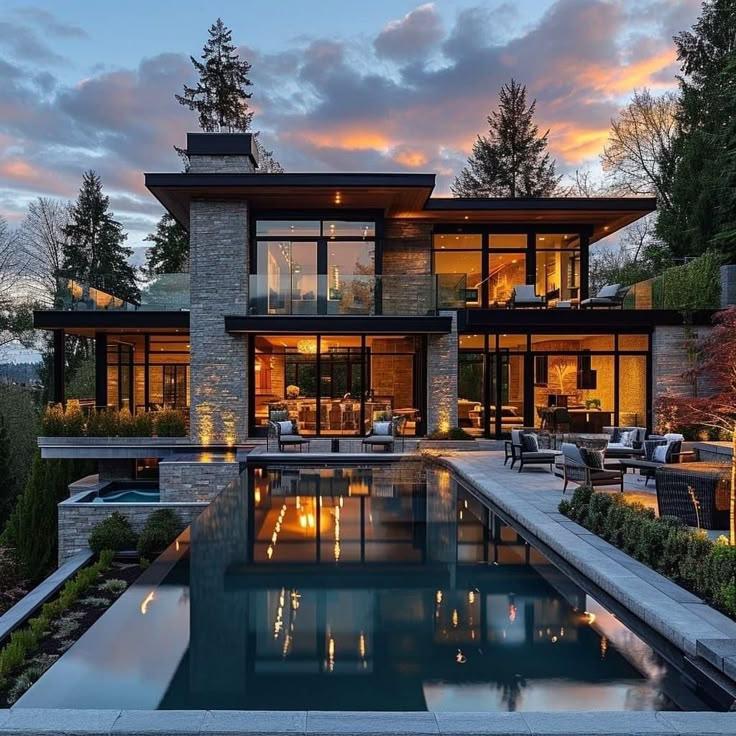 A luxury residence with illuminated interiors and a pool at twilight