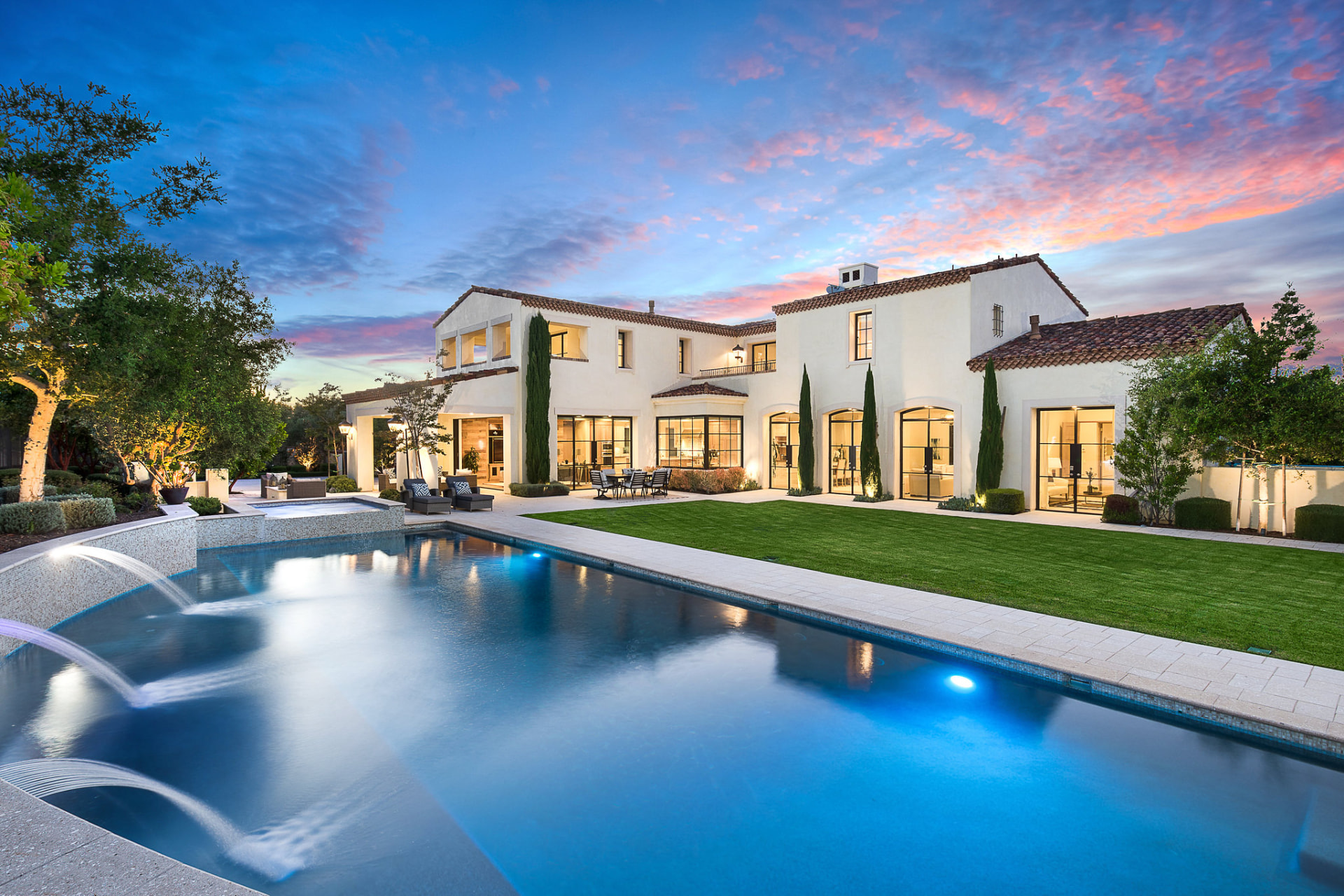 White villa with pool and lawn at twilight