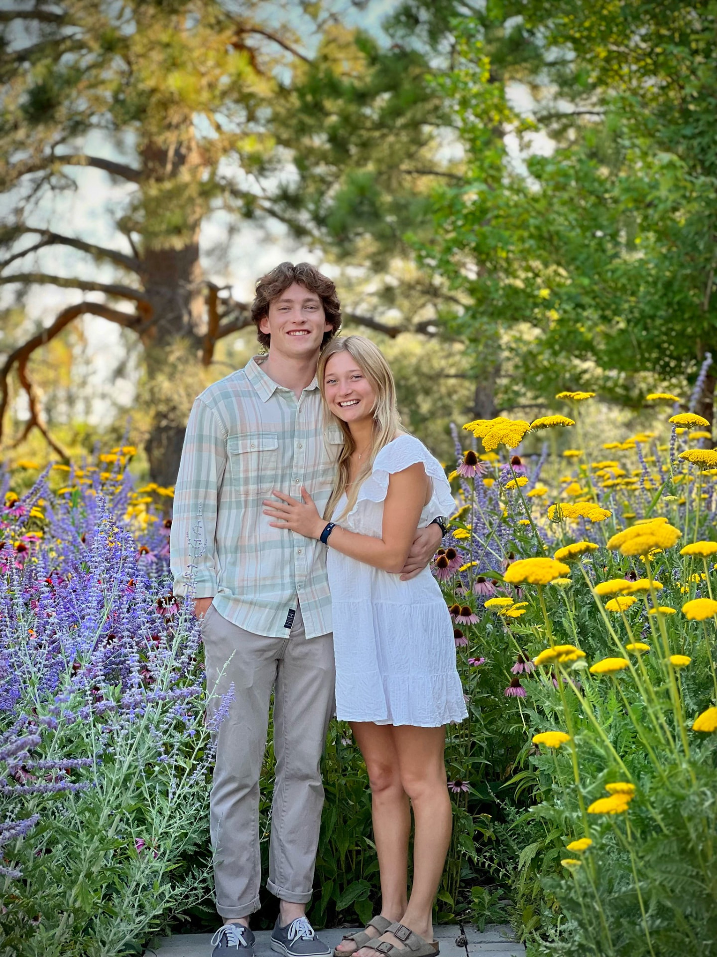 Smiling couple standing among blooming garden flowers