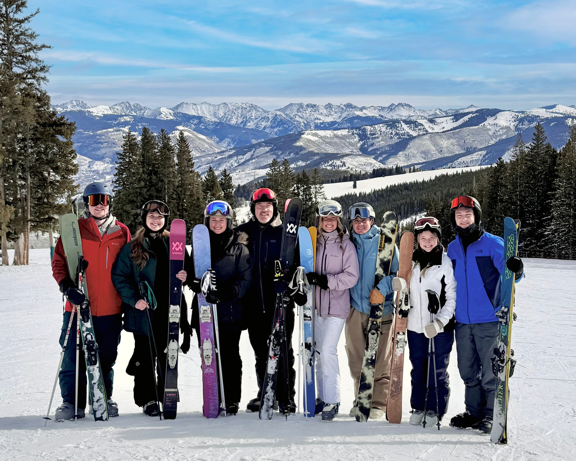 Group of skiers posing together with mountain peaks behind them